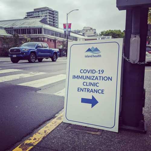 A sandwich board with the Island Health logo and "COVID-19 Immunization Clinic" written on it.