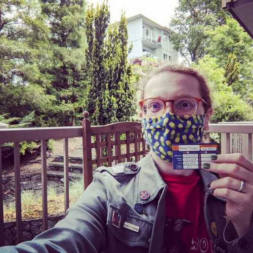 Me wearing a mask and holding up my vaccination record.